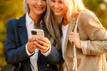 Mature multiracial businesswomen using cellphone during meeting