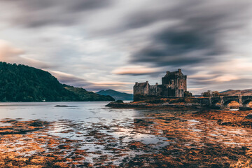 Canvas Print - Ancient historic Eilean Donan Castle in the Western Highlands of Scotland under a cloudy sunset sky