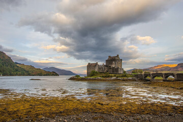 Canvas Print - Ancient historic Eilean Donan Castle in the Western Highlands of Scotland under a cloudy sunset sky