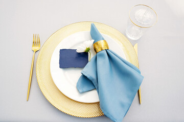 Wall Mural - Elegant and chic wedding table setting in gold and blue colors and fresh flowers. Soft selective focus.