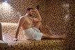 © zinkevych - A man in a towel sitting in sauna and having detox session