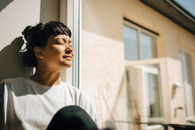 Woman With Bangs Sitting In Sunlight Near Window At Home