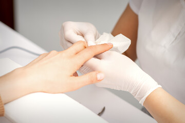 Wall Mural - Manicure master wiping the moisturizer from the end of female fingers in beauty salon