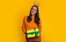 Beautiful Happy Stylish Woman In Christmas Sweater With Present Box In Hands Is Posing Isolated On Yellow Background