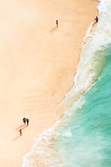 Wall Mural - View from above, stunning aerial view of some people relaxing on a beautiful beach bathed by a turquoise sea during sunset. Kelingking beach, Nusa Penida, Indonesia.