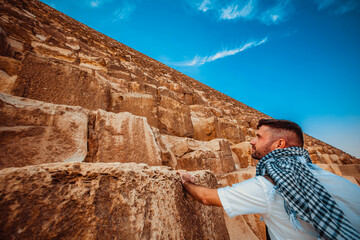 A man tourist stands near the huge blocks of the Giza pyramid near Cairo.