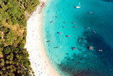 Fototapeta Sypialnia - View from above, stunning aerial view of a white sand beach bathed by a turquoise, clear water. Tropical beach with some long tail boats and relaxed tourists. Freedom beach, Phuket, Thailand.