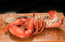 Top View, Medium Distance Of A Steamed, Two And Half Pound Lobster With Tail Split, Shell Cutting Sheers And Glass Bowl Of Melted Butter, On A Wood Cutting Board