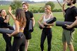© rh2010 - European people with fitness mats standing and talking in green meadow. Friends practicing yoga and doing sport exercises. Concept of healthy lifestyle. Athletic men and women wearing sportswear
