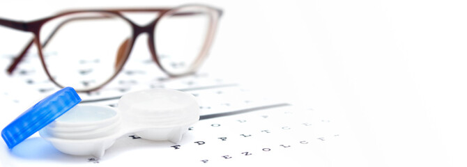 Contact lenses case and eye glasses on and eye test chart. Vision concept. Way to improve vision