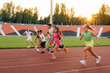 © Andrii - A large group of children, boys and girls, run and play sports at the stadium during sunset. A healthy lifestyle.