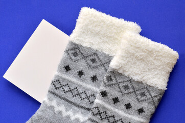 Wall Mural - gray warm socks and card with place for text on blue background, mockup