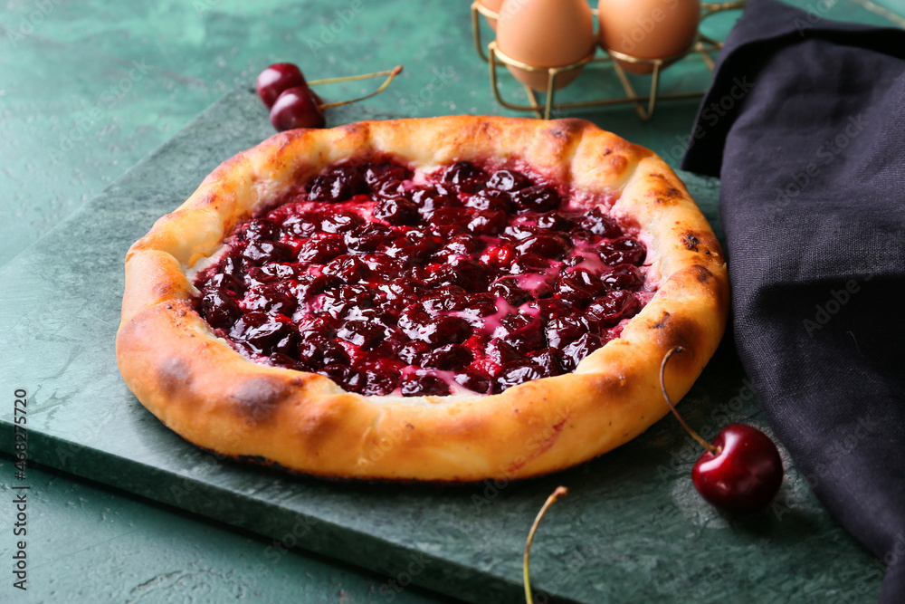 Board with tasty cherry khachapuri on color background, closeup