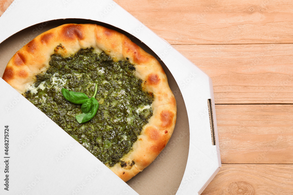 Cardboard box with tasty khachapuri on wooden background