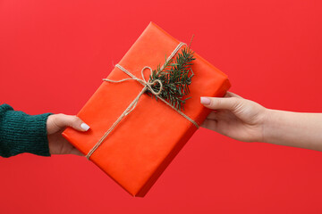 Women holding Christmas box on red background, closeup