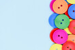 © NikonLamp - Vivid colored wooden buttons on blue background. Bright multicolored round buttons border close up. Eco recycle sewing and needlework concept with copy space.