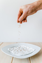 Seed of garden cress spread on white plate with wet paper towel in front of white background