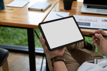 Cropped shot of a man sitting at modern office room and using blank white screen tablet, businessman using pen stylus