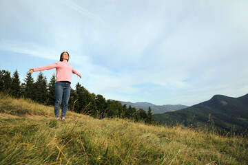 Wall Mural - Young woman enjoying mountain landscape. Space for text