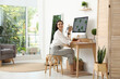 © New Africa - Young woman working at table in light room. Home office