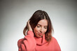 © arts - young shy woman portrait in pink sweater on studio background