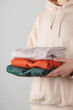 Stack of autumn basic women's turtlenecks in trendy colors in female hands. Minimalist basic wardrobe. Household laundry and decluttering.