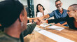 © Jacob Lund - Diverse group of businesspeople bringing their fists together in a boardroom