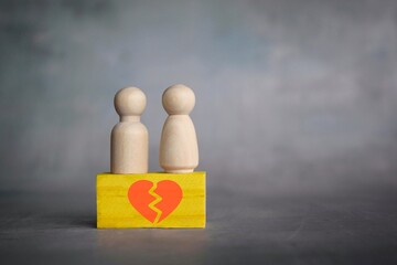 Divorce and broken relationship concept. Wooden dolls and wooden block with broken heart icon.