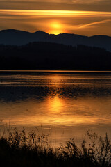 Wall Mural - Sunset over mountains. Reflection on water surface. Colorful twilight sky