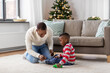 family, winter holidays and people concept - happy smiling african american father and baby son playing with toy car at home on christmas