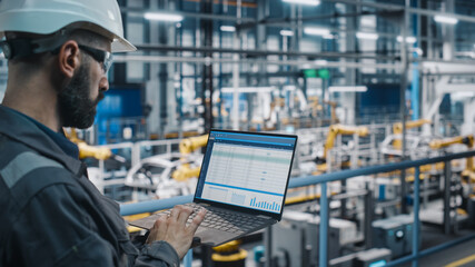 Poster - Car Factory Engineer in Work Uniform Using Laptop Computer with Spreadsheet Software. Working with Software at Automotive Industrial Manufacturing Facility Dedicated for Vehicle Production.