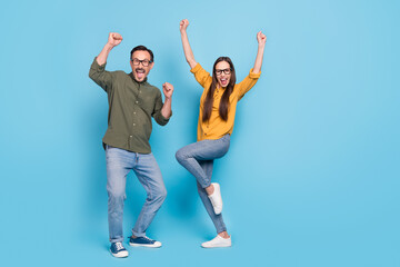 Full length photo of mature happy man and woman couple winner raise fists isolated on blue color background