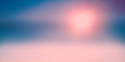 Blurred rising sun over the blue ocean and pink fog.