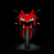 Red Sports Bike In The Dark. Two Lights. Front View. Isolated On A Black Background