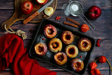 Wall Mural - Top view of baked red apples on a baking sheet on a dark wooden background.