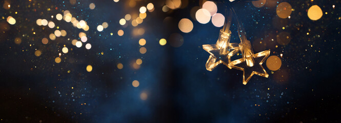 Wall Mural - christmas warm gold garland lights over dark background with glitter overlay
