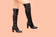 © Анастасия Бурлакова - Woman's Caucasian sexy legs in shiny black brown patent leather high stiletto high heels boots isolated on light peach pink background. One legs up, step, copy space in right side, closeup, sexy mood