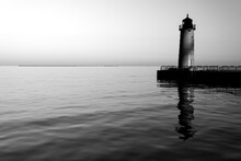A Black And White Image Of A Lighthouse On A Pier