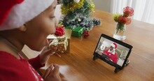 African American Woman With Santa Hat Using Tablet For Christmas Video Call With Santa On Screen