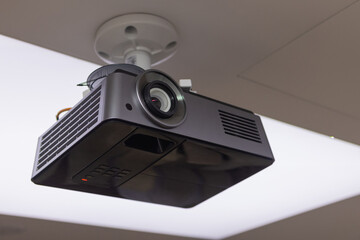 A black overhead projector on ceiling in a conference room modern classroom color toned image.