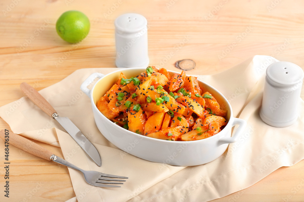 Baking dish with honey chilli potato on wooden background