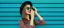 Portrait Of Happy Smiling Young Woman Photographer With Vintage Film Camera On Colorful Blue Background