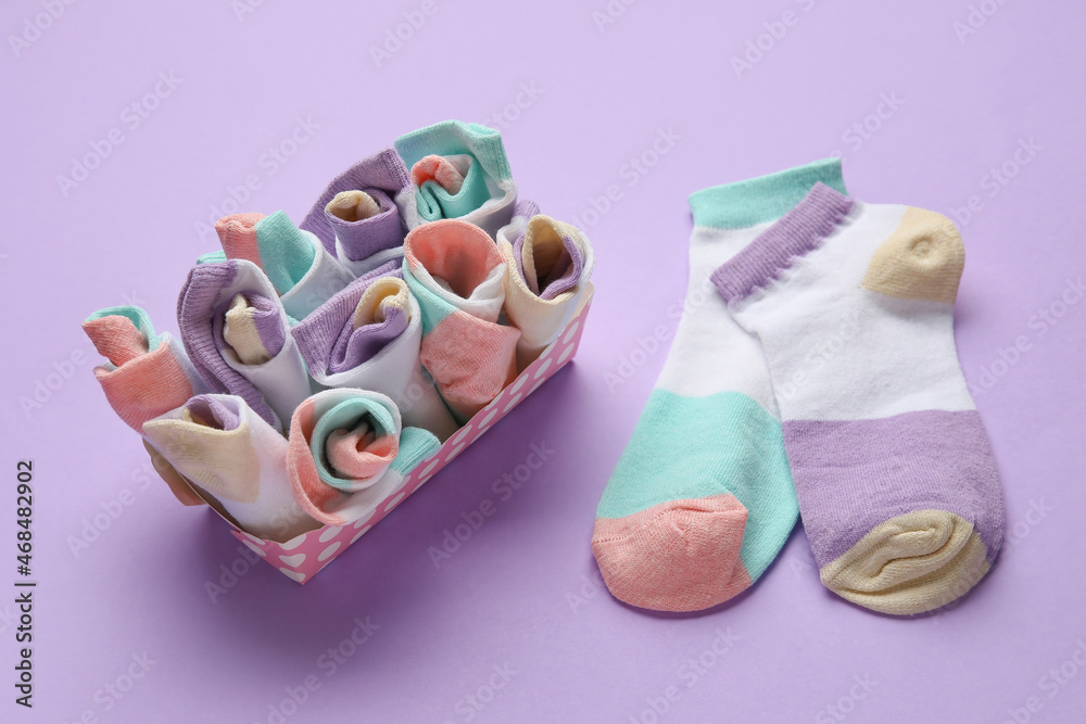 Box with many different socks on color background