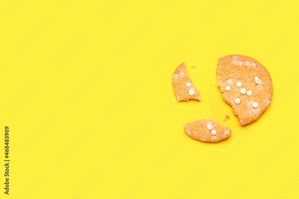 Tasty broken cookie with chocolate chips on color background