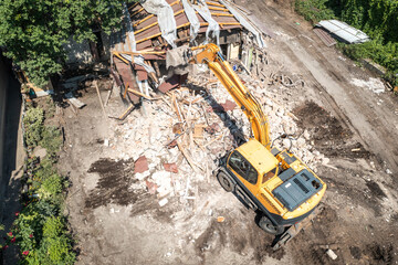 Wall Mural - Demolition of building aerial view from drone. Excavator breaks old house.