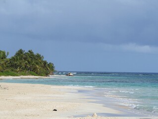 Wall Mural - Waves rolling into a white sand Flamenco beach in Culebra, Puerto Rico, with an old tanker in the distance.