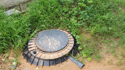 Black PE septic tank. Plastic septic tank is buried in the ground with green grass for treating waste on the construction site with copy space. Close-up and selected focus