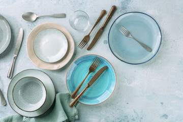 Modern tableware set with cutlery and a vibrant blue plate, overhead flat lay shot with copy space