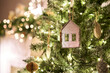 © malkovkosta - Christmas tree decorated. Close-up a small house, Cones, garland, and other Christmas tree toys. light from the garlands