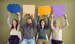© Studio Romantic - Group of happy people holding up clean, colorful mock up paper banners. Four smiling males and females sitting in row and showing blue, orange and purple speech balloons and message bubbles